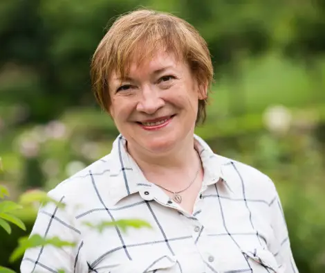 Smiling woman featured with a Village Pest Services lawn care testimonial